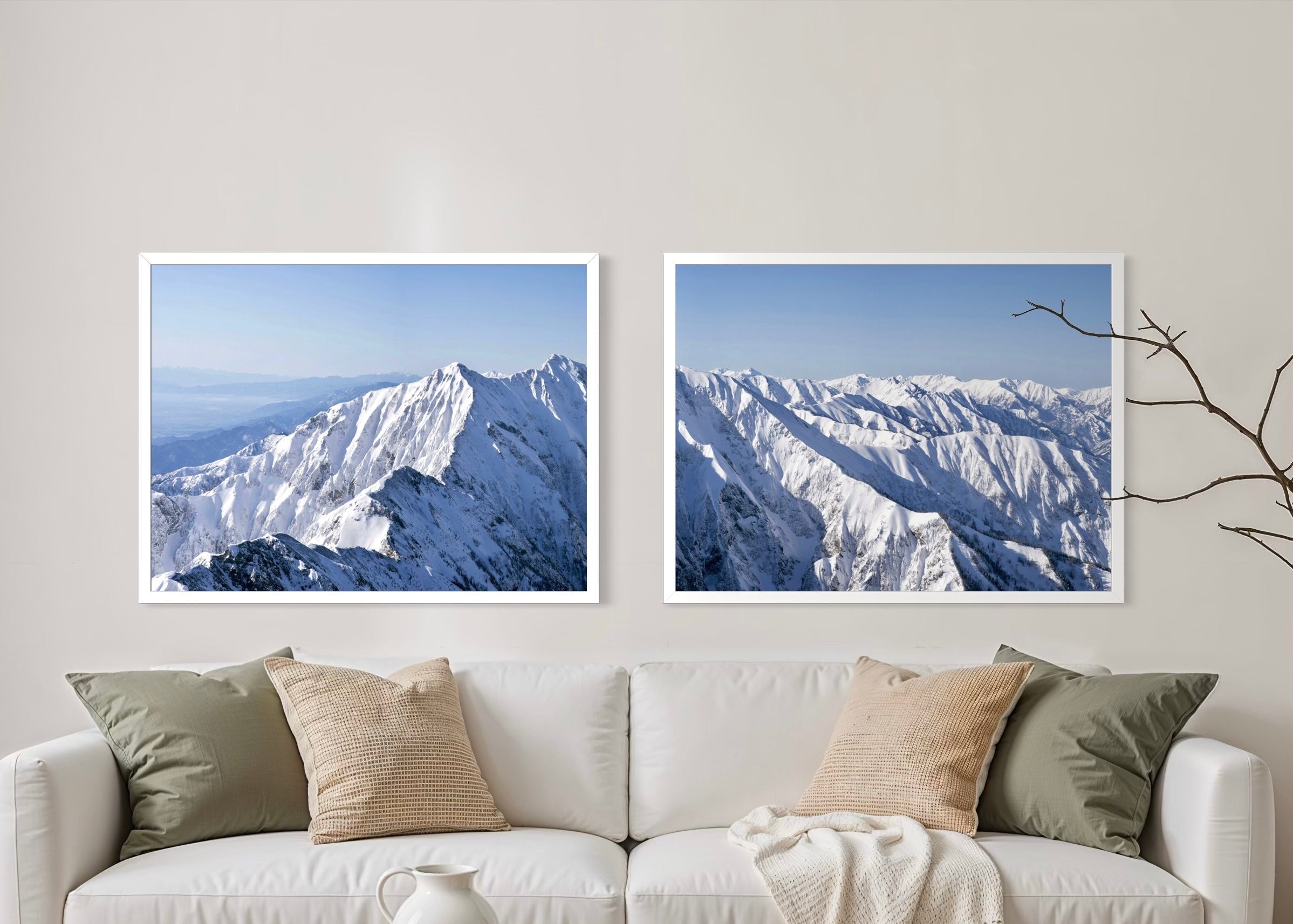 Living room with a white sofa, wooden coffee table, and two mountain landscape paintings on the wall.